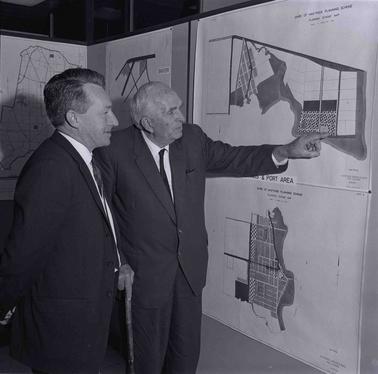 Two men examining a notice board.