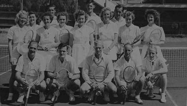 A group of eight men and eight women wearing tennis whites and holding tennis racquets posing for a photo in three rows.