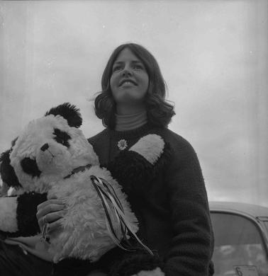 A young woman holding a large soft toy bear.