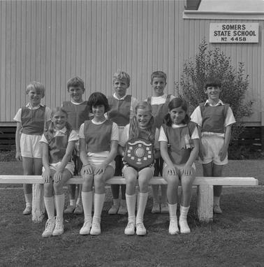 Four girls and fve boys in sports clothing holding an honour plaque posing for a photo in two rows outside Somers Primary School.