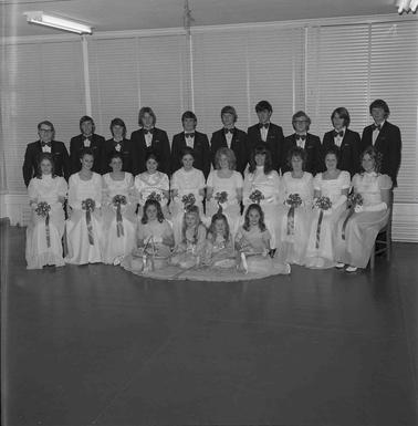 Ten young couples in formal attire, all girls wearing white ball gowns and four younger girls posing for the photograph in three rows.