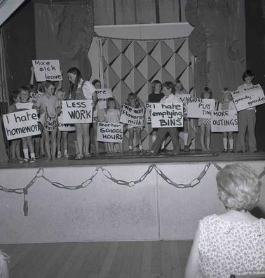 Young children holding protest plackards gathered on a stage.