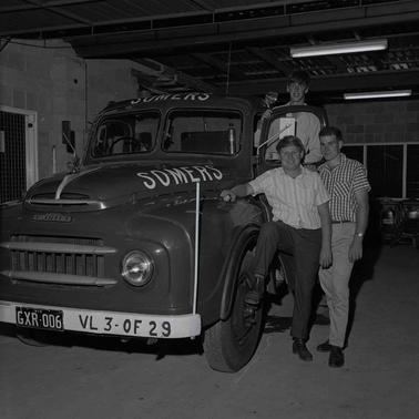 Three young men posing at an Austin truck with ‘Somers’ signage on the front of the roof and on the bonnet.