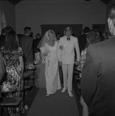 A bridal couple walking up the church isle with the congregation standing on both sides.