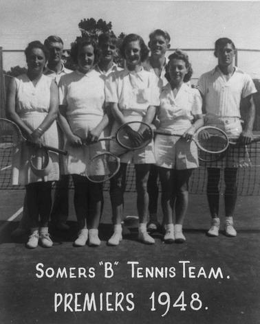 Eight adults dressed in tennis whites posing for a photograph.