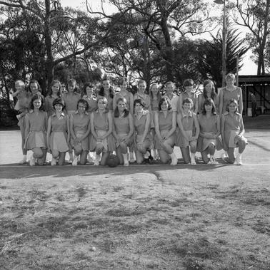 Two rows of girls in netball uniforms posing for a photograph.