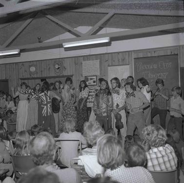 A large group of young people performing on a dias in front of an audience.