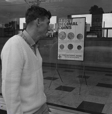 A man inspecting a notice on a shop window.
