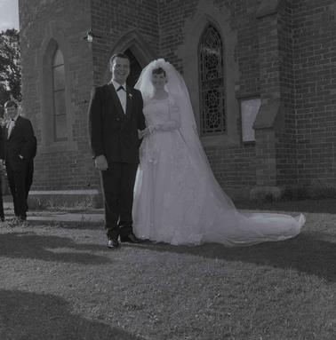 A bride and groom in front of a brick church.