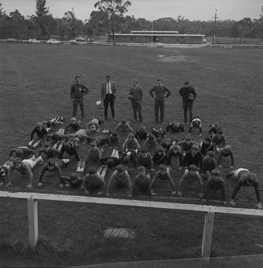 A teaam of young football players doing pushups.