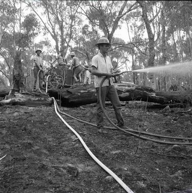 One man holding a fire hose, four others in the backgrouno date.