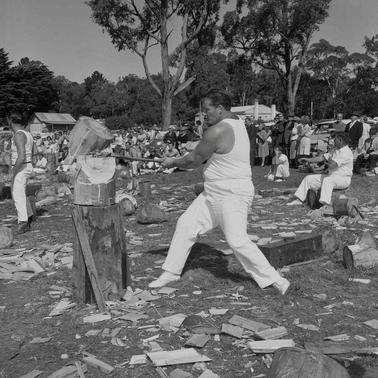 Red Hill Show Woodchopping event . A man in a singlet swinging an axe at a log.