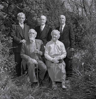 Four men and a woman, man and woman seated, posing for a photograph.