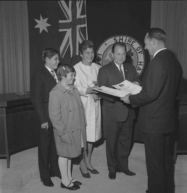 A family group of four with a man holding some documents.