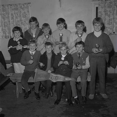 Nine young boys a photo in two rows.  Boys in the front row are holding a pennant.