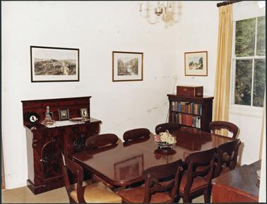 The dining room at Southdene featuring mahogany table and seven chairs, small sideboard, bookcase
and three paintings on the wall