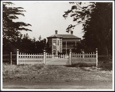 A two story Italianiate style house patterned multi coloured brickwork hipped slate roof two chimneys skillion verandah bay window to two floors front fence picket with capped posts gateway in centre with house name in centre