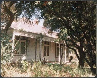A white weather board house with verandah surround and iron roof