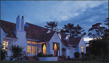 Calendar photograph, white stuccoed, Spanish style with projecting bays, multiple gables, double chimney, steps to front English style porch, landscaped front garden