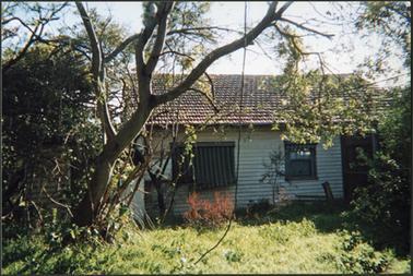 A rear view of a c 1920s weather board cottage with an unkempt garden