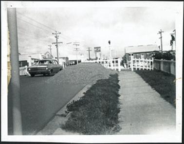 A car crossing railway line, wig wag signal, man up a pole on right ‘ Beware of Trains’ sign, gabled roof building on right which is the AEUSA Building used for Girl Guides, AEUSA meeting hall for returned servicemen