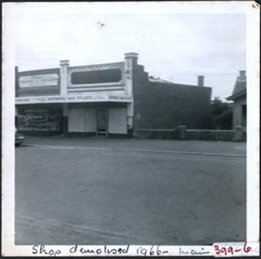 Two shops with parapets with square rises at each end, house next door on right, shops demolished in 1966 