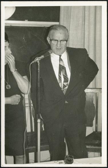 Dr K. Bowden speaking at the microphone at the launch of the Westernport Book Sale at Ballam Park in 1970, Mrs Leslie Moorhead can be partly seen standing on the left of the photograph