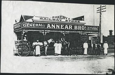 View of the Annear Brothers, General Store, Mornington, opposite Grand Hotel a group of people are standing out the front of the shop two horse drawn carts are also situated out the front of the shop an electrical pole is situated to the right of the building
