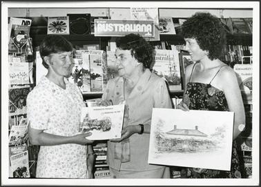 A photo of Leslie Moorhead, Joan Bagnuda and Diane White with pictures of heritage houses 