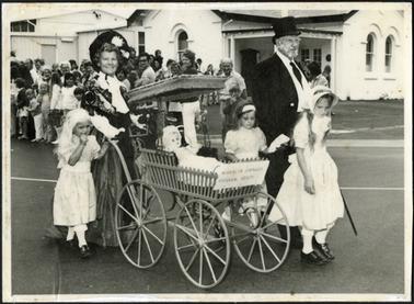 Members of Historical Society dressed in period costume  pushing antique pram in the Australia Day Parade, the group comprising of a man, woman and three girls are standing on the road outside the Mornington Peninsula Historical Society