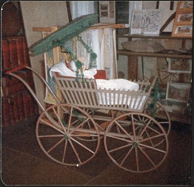 A frontal view of the American heritage pram with the hood open doll sitting in the pram