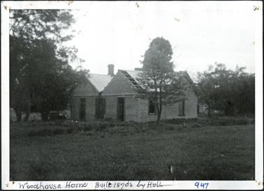 A side view of a hipped roof building wooden structure, several windows one chimney