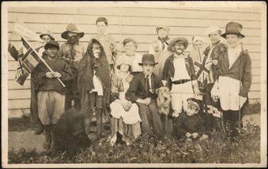 A group of children in fancy dress costumes with one adult in centre of photograph