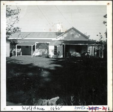 A back view of Wolfdene, weatherboard with a multi gabled roof form, and has an encircling skillion form verandah, the roof is corrugated iron
