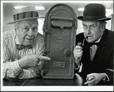 This image is of Clarence Rawlings, Asst Secretary and Neil Taylor, President, photographed on either side of
the mail box, August 1989. Both are in period costumes