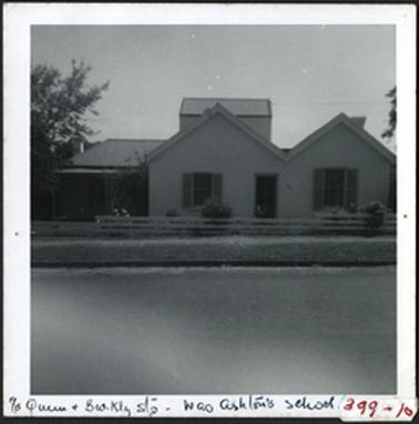A double fronted home divided by doorway. Hipped roofs and it would appear a loft or stables in background