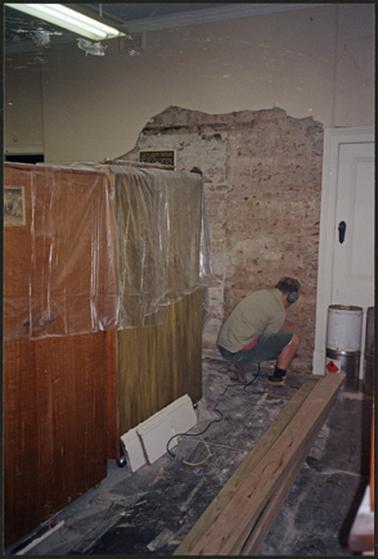 The image shows a workman treating the rising damp in the entry hall