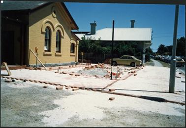 A side view of part of the freshly painted building with the paving work well in progress, the Old Bank Cafe in the background to the right of the photo