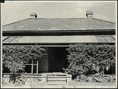 A front view of  ‘The Briars’, with verandah and steps leading down to garden a hipped roof and two chimneys
visible