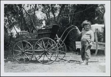 Child standing with her hand on pram