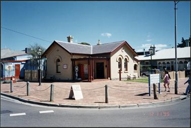 Corner view of Post Office Museum, showing Salvation Army kiosk advertisements in front and also the left hand side, to right hand side the Old Bank Cafe