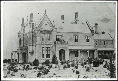 The two storeyed stucco house is symmetrically composed with a single storeyed timber verandah and stucco porch steeply pitched slate roofs, prominent chimneys and decorated gable ends original buildings are Gothic Revival