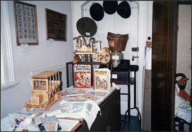 On display collection of childrens’ books and wooden toys  also on wall behind collection of hats, hat box and walking sticks for Heritage Week 1991
