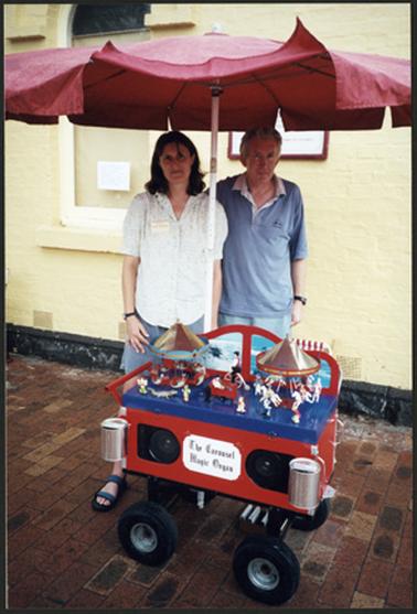Maureen and Colin Tregonning standing behind the carousel outside OPOM Mornington, Australia Day 2001