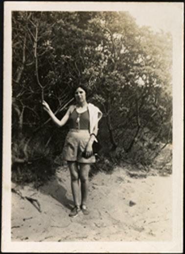 The image shows a Bradford family member standing on sand near teatree 