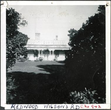 Image taken in the garden of Redwood a house with hipped roof, two chimneys, verandah and established
gardens