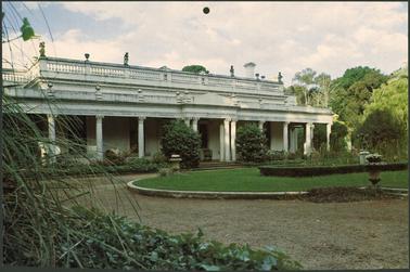 The image shows the sweeping driveway going up to the house and the established gardens