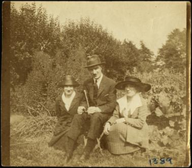 The image is of the Bradford family one male sitting and a female on either side of him, photographed in a garden setting