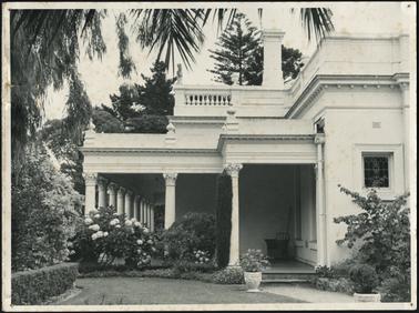 A side view of Beleura and entrance to the verandah, established gardens and ornamental urns