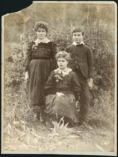 The image shows three of the Drayton family children, two girls and one boy, the photo taken in an outside setting